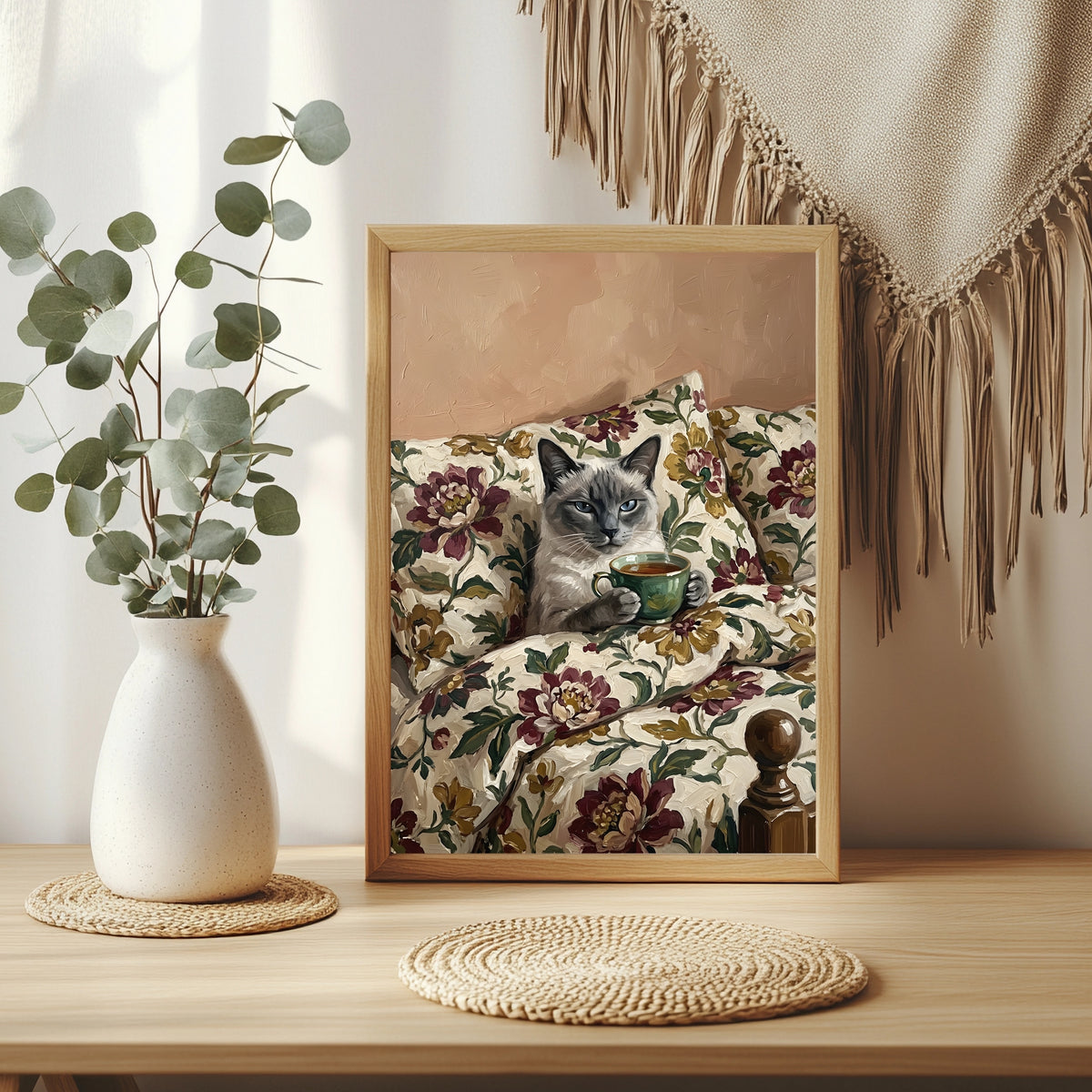 Siamkatze mit blauen Augen hält eine Teetasse auf geblümtem Sofa